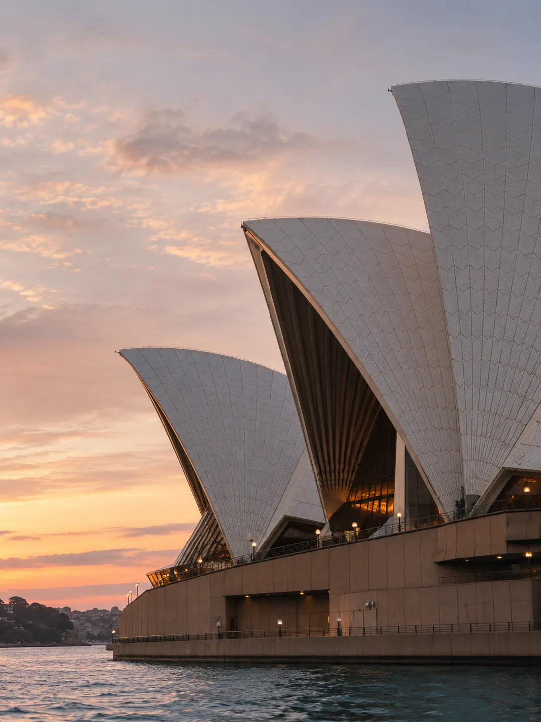 Sydney Opera House shells in close-up at sunset, with a pink and orange sky above the harbour