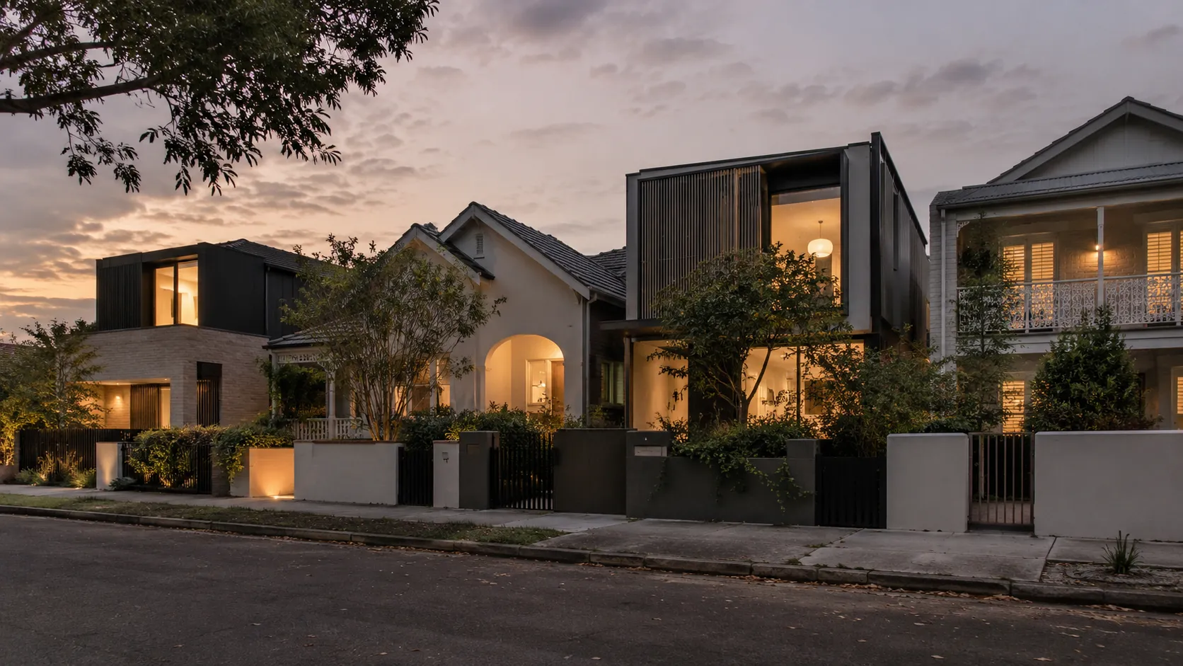 A street of houses at dusk, with dark-clad modern additions and a slatted-screen front beside period homes behind rendered walls