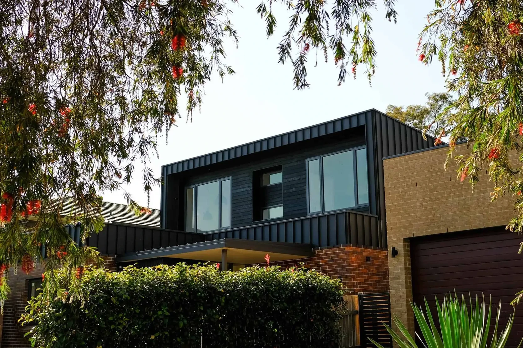 Two-storey home with dark standing-seam metal cladding and roofing above brick